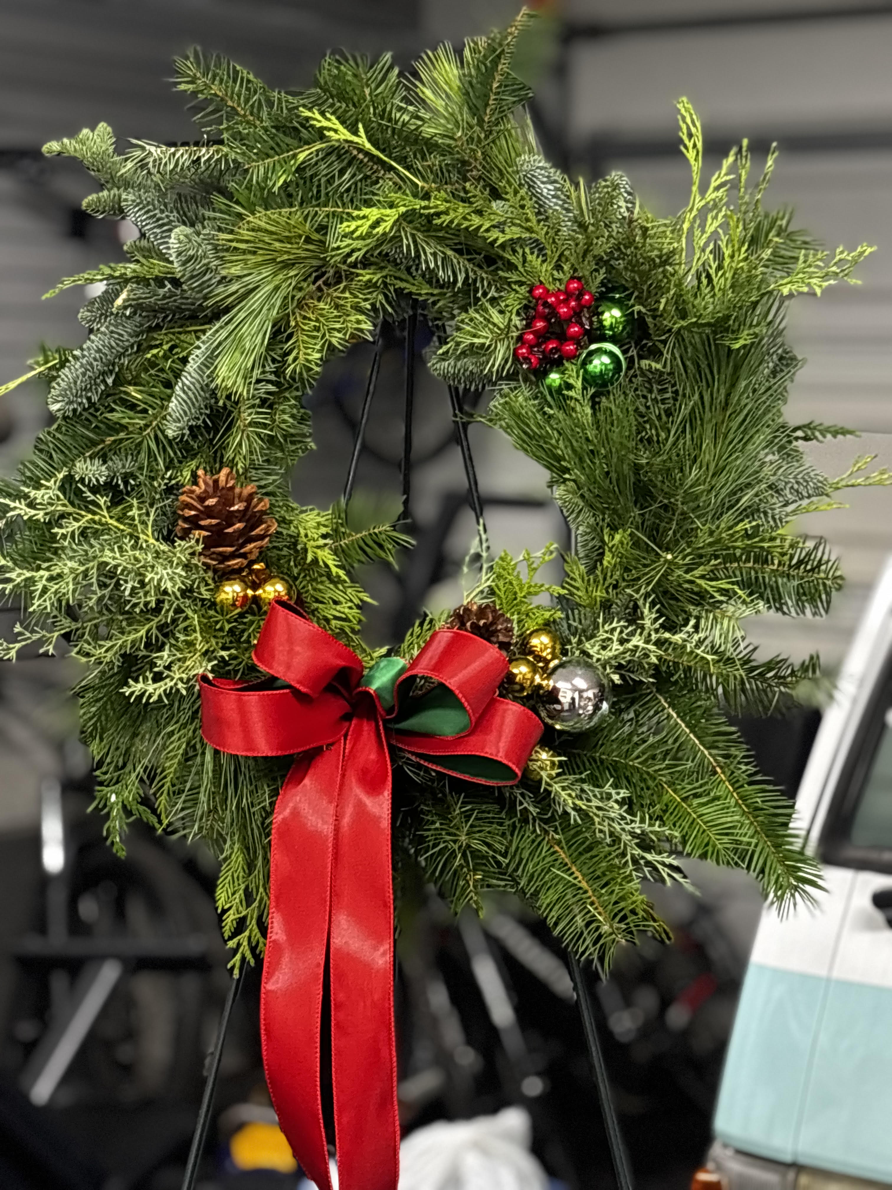 Fresh evergreen holiday wreath with pinecones, ornaments and a red bow